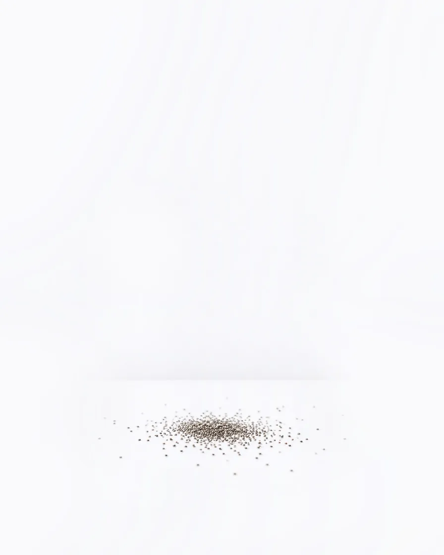 A white studio tabletop with a small spill of chia seeds.