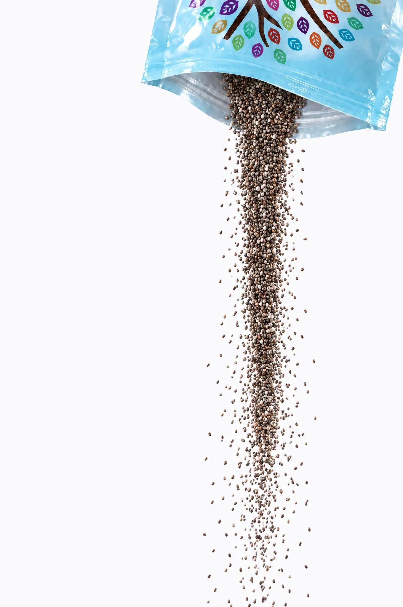 Chia seed pouring in a long stream from the open mouth of a tipped-over E'LAN pouch, its sky-blue film and coloured leaves just visible at the top edge, the seed falling away past the bottom.